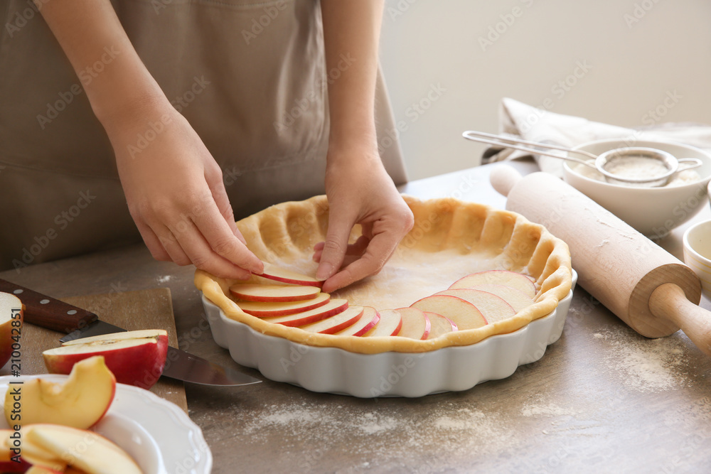 Woman preparing apple pie at table