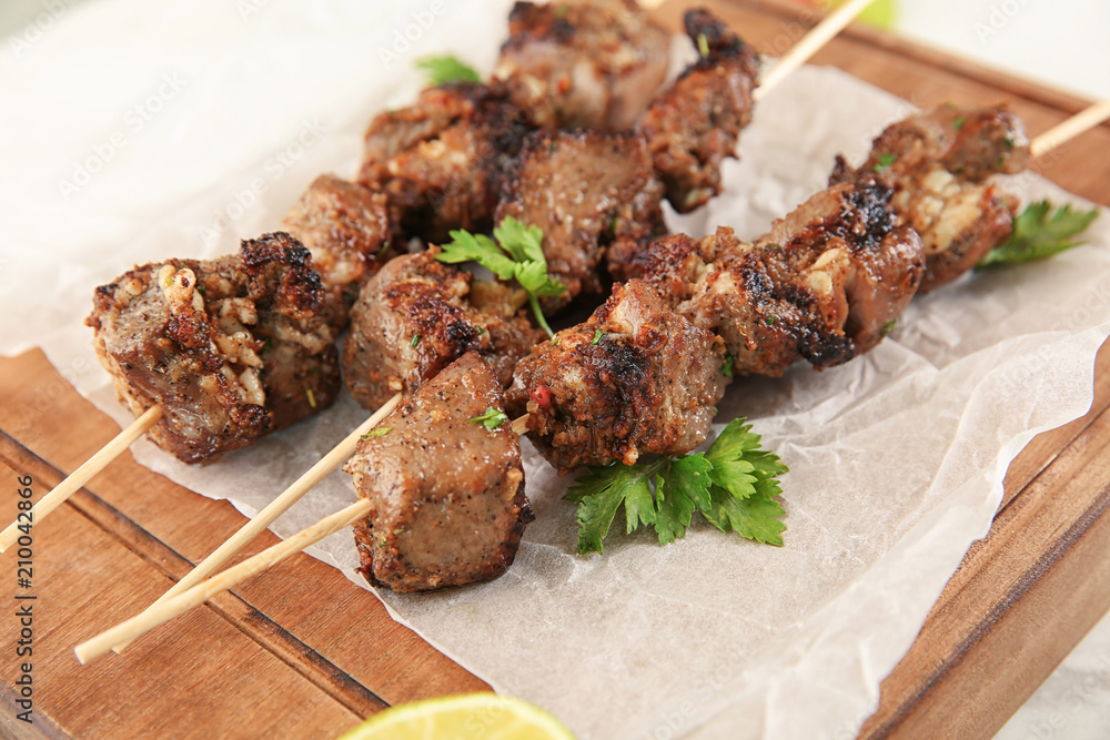 Barbecue skewers with juicy meat on wooden board, closeup