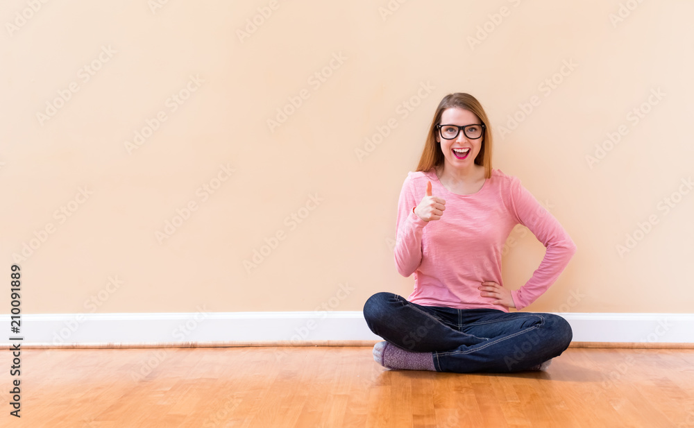 Happy young woman giving the thumbs up in a big open room