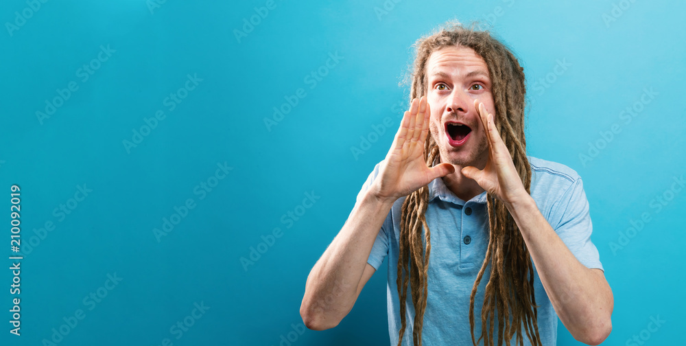 Young man shouting a message on a solid background