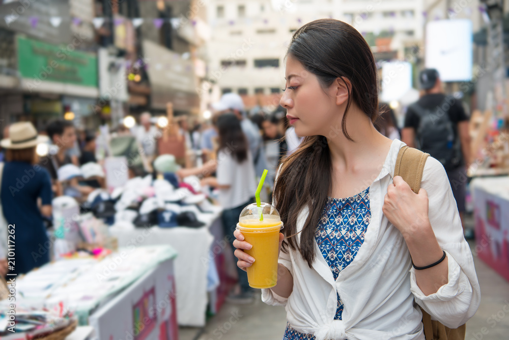 女人拿着一杯芒果汁走着