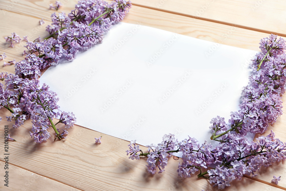 Composition with blank card and blossoming lilac on wooden background