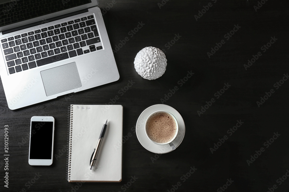 Composition with empty to-do list, laptop and phone on dark background