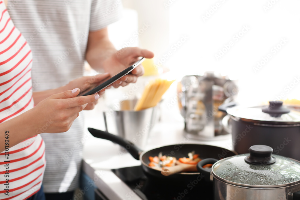 年轻夫妇在厨房里用平板电脑阅读电脑食谱