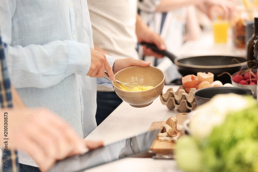 Young woman cooking with friends in kitchen