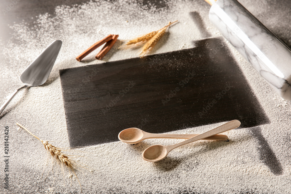 Frame made of flour and kitchen utensils on dark background