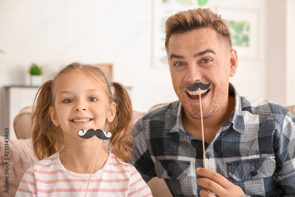 Happy father and daughter playing with party decor at home