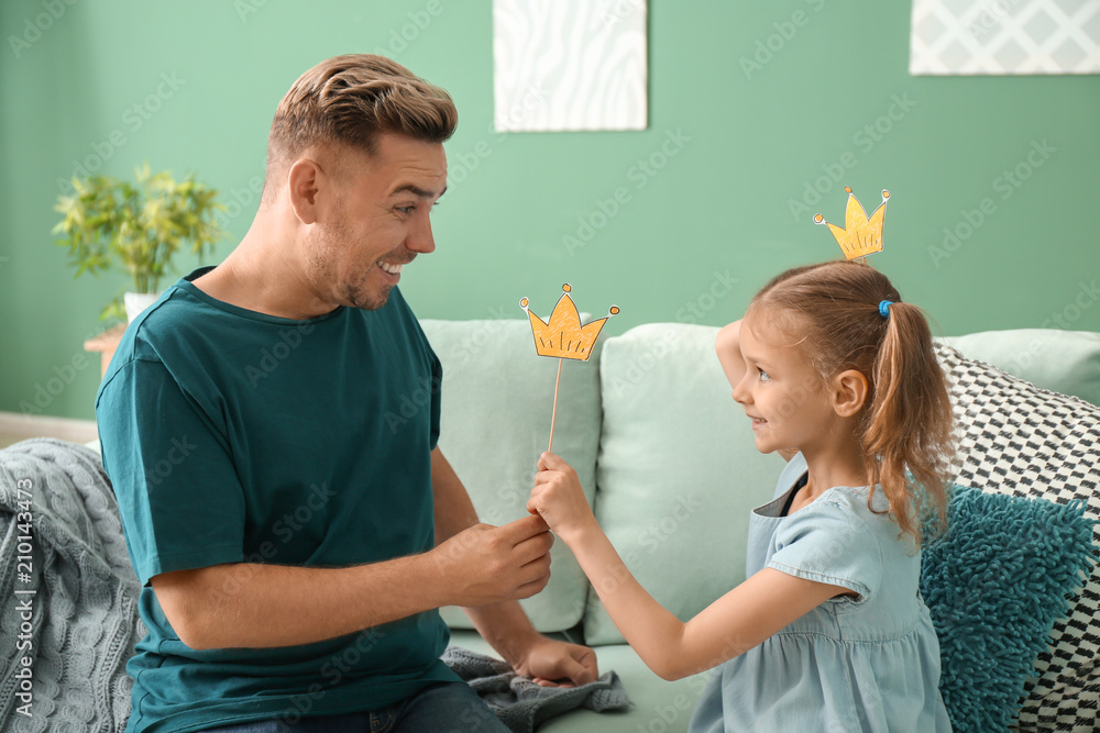 Happy father and daughter playing with party decor at home