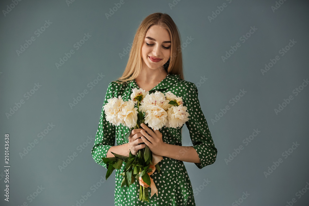 Attractive young woman with beautiful flowers on color background