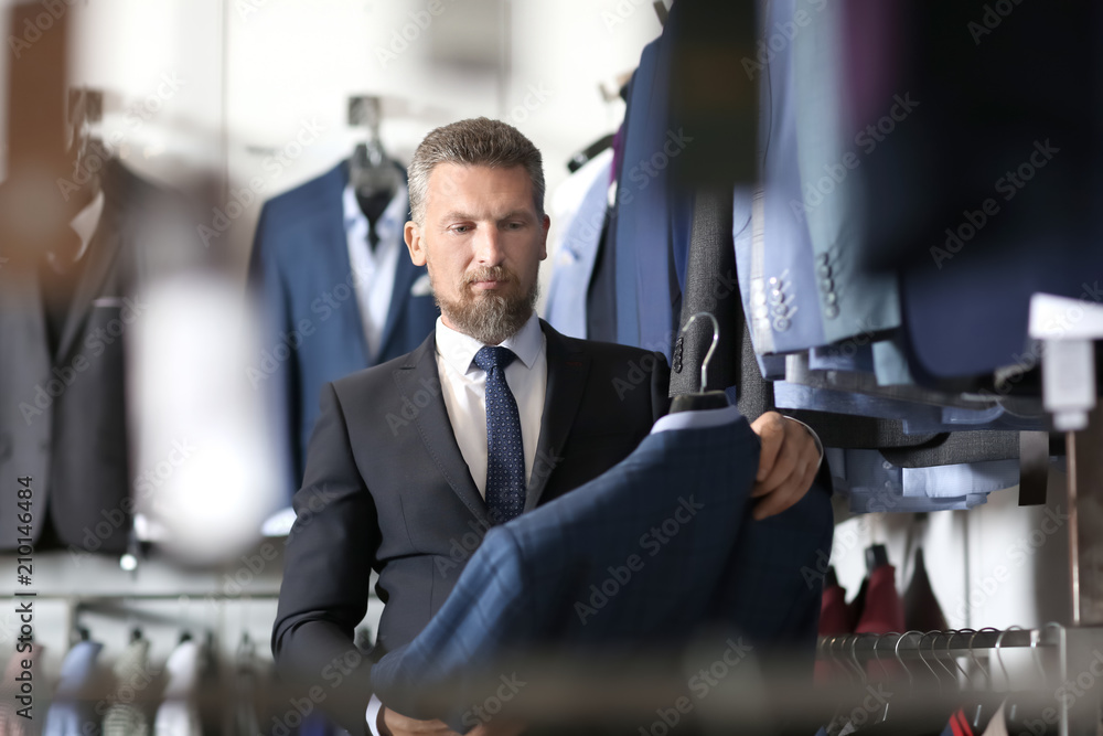 Handsome mature man choosing clothes in store