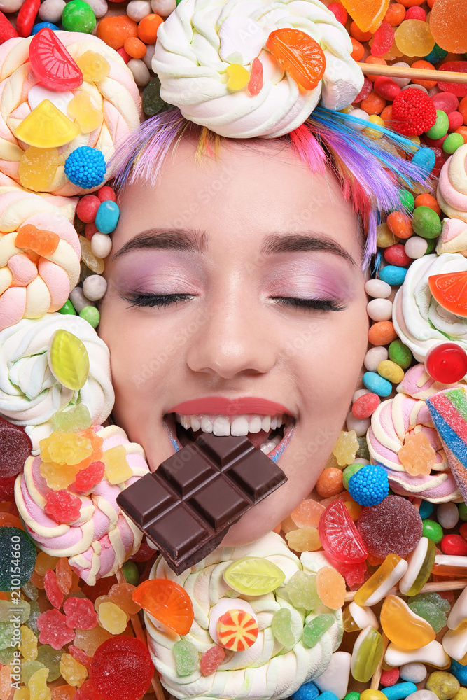 Face of beautiful young woman with creative makeup surrounded by different sweets