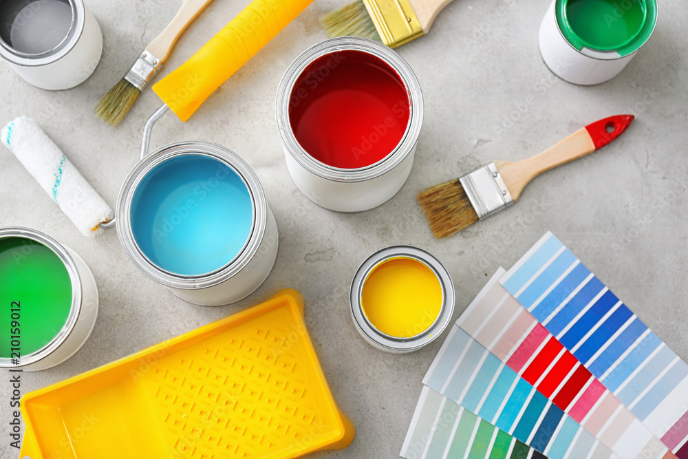 Composition with cans of paint, roller and brush on light background