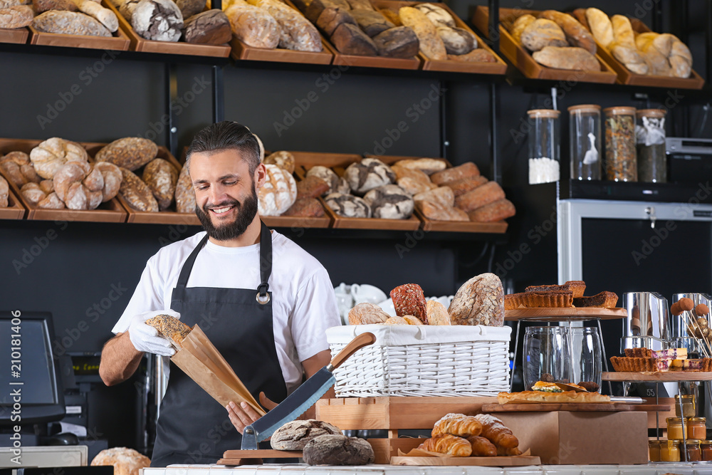 Young man packaging bread for customer in bakery