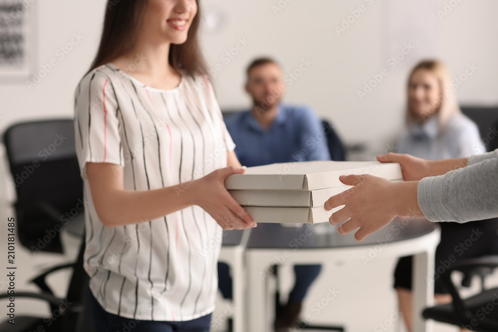 Young man delivering cardboard pizza boxes to client in office