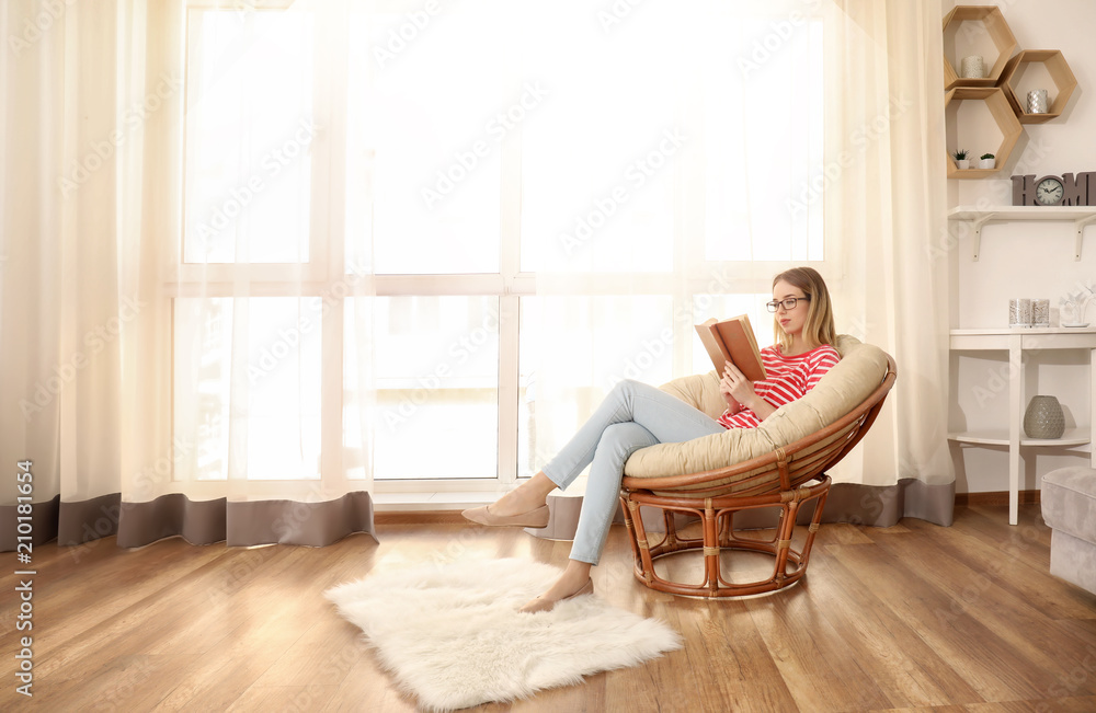 Young woman reading interesting book at home