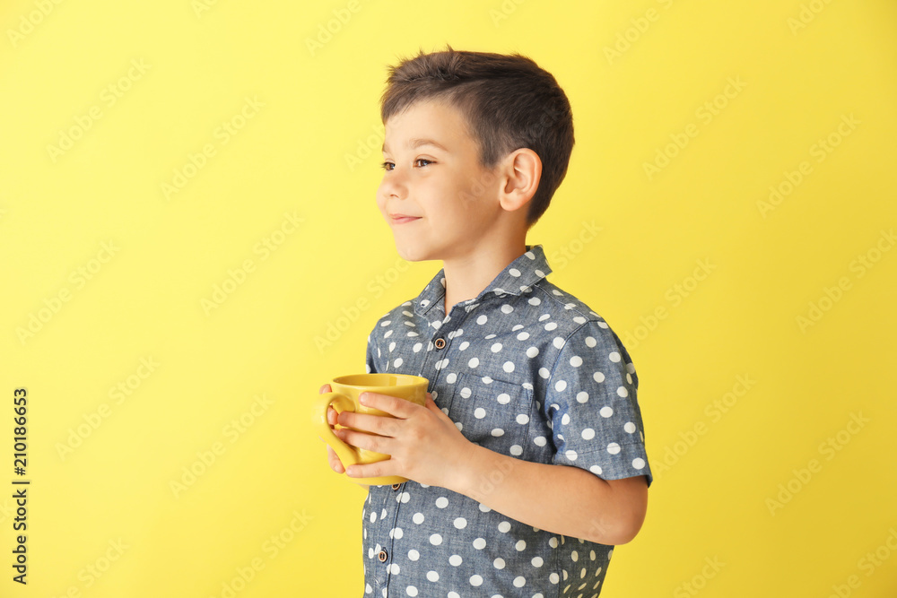 Cute little boy with cup of hot cocoa drink on color background