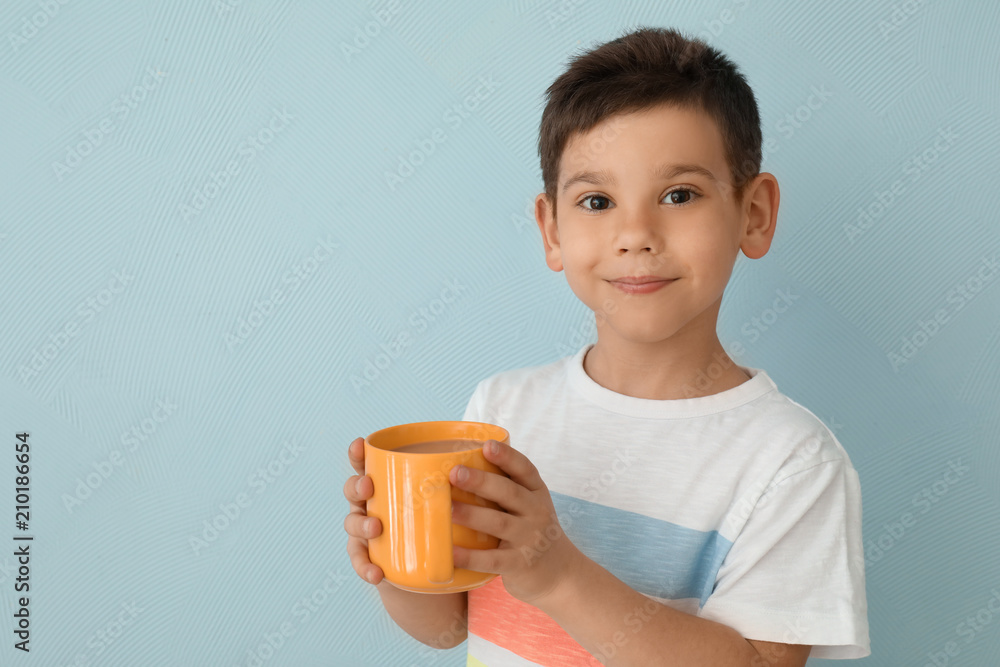 可爱的小男孩，浅色背景下有一杯热可可饮料