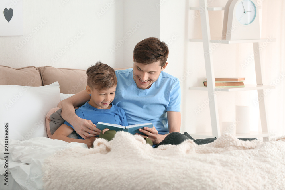 Father and his son reading book together at home