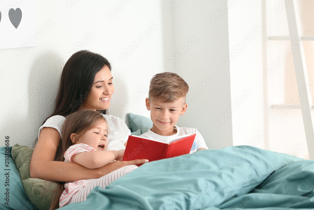 Mother and her children reading book together at home