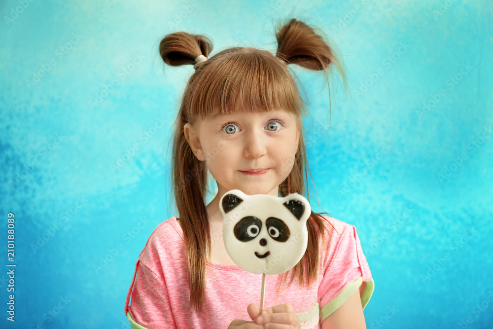 Cute little girl with lollipop on color background