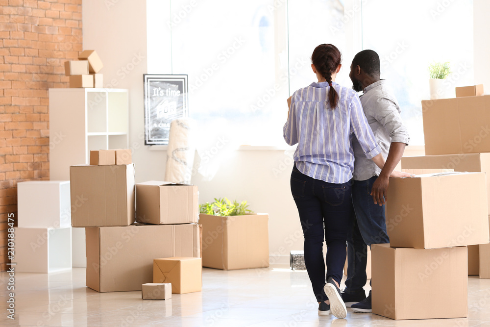 Interracial couple with boxes indoors. Moving into new house