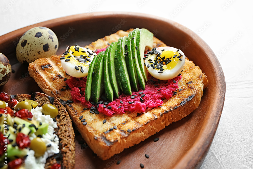 Plate with tasty toasts on light background, closeup