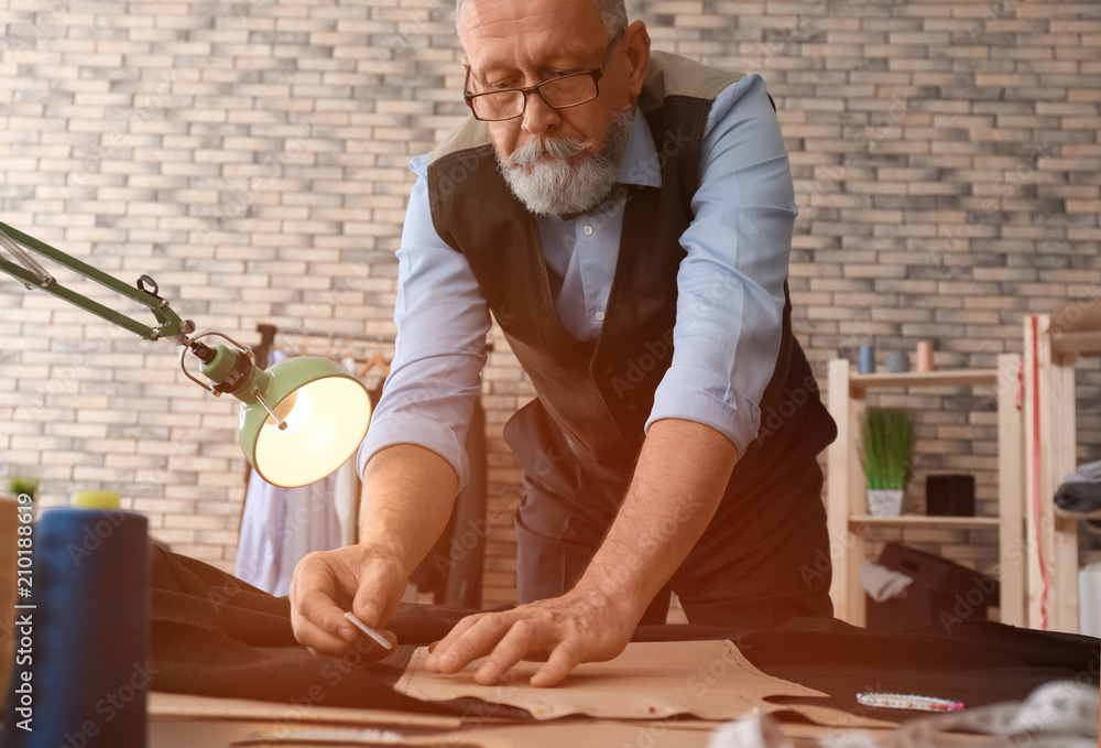 Mature tailor working with sewing pattern in atelier