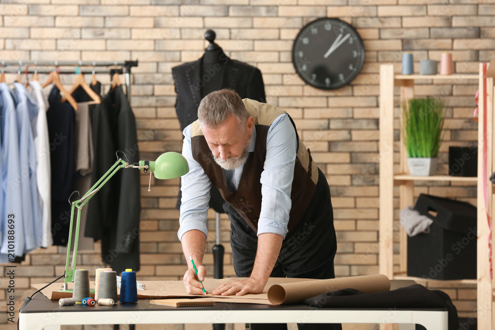 Mature tailor working with sewing pattern in atelier