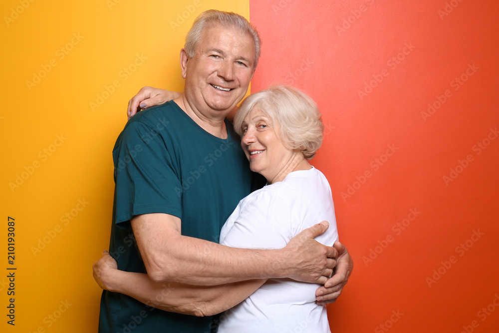 Happy senior couple on color background