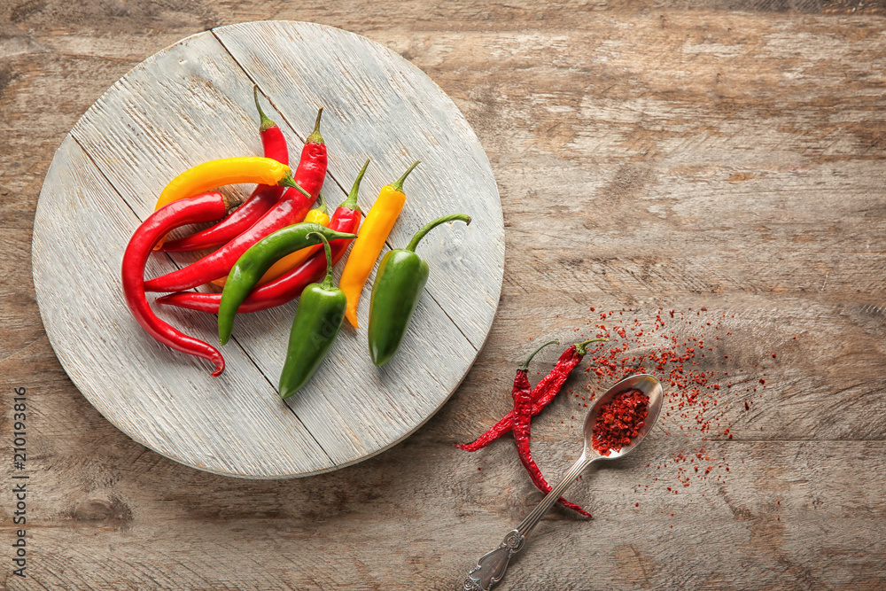 Stand with different fresh chili peppers on wooden background