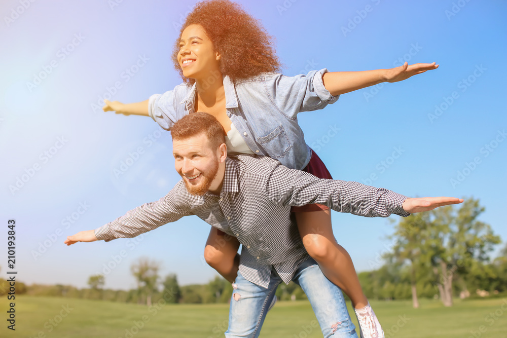 Young loving interracial couple having fun outdoors on spring day