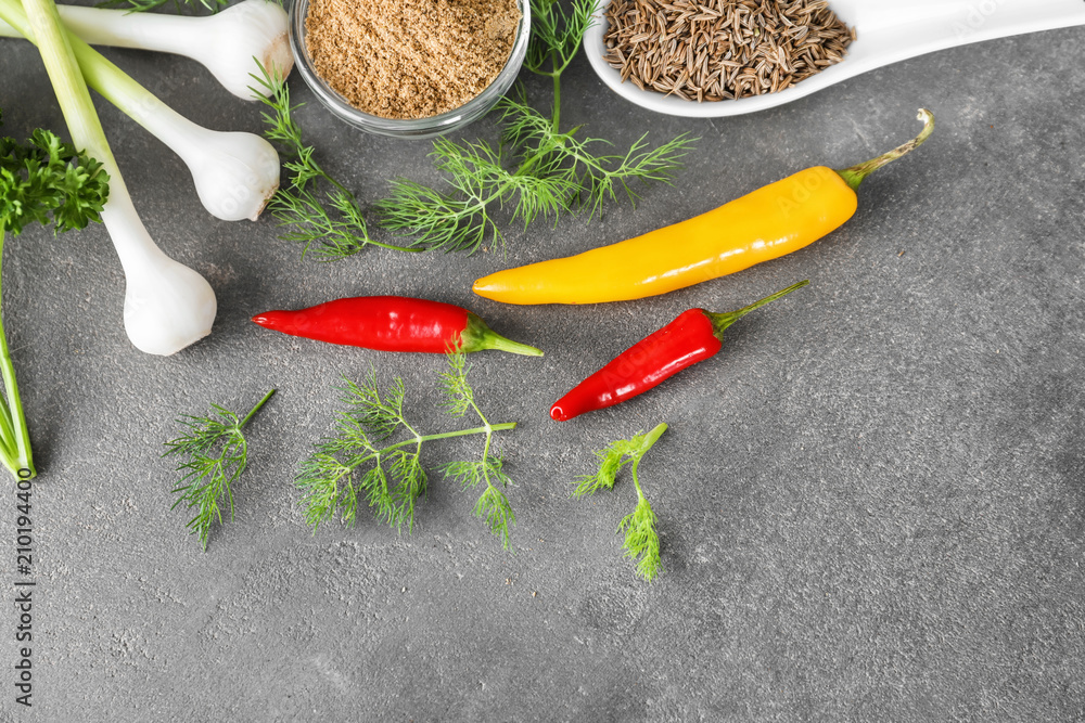 Various fresh herbs with dry spices on grey textured background