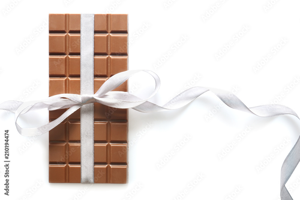 Tasty milk chocolate bar with ribbon on white background