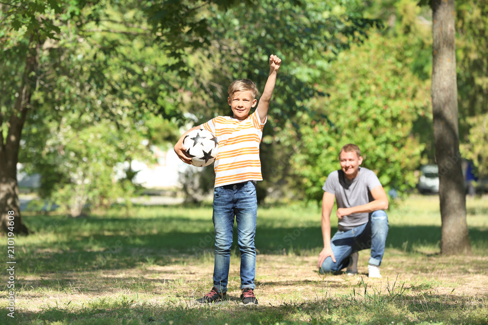 Happy father and son playing football in park