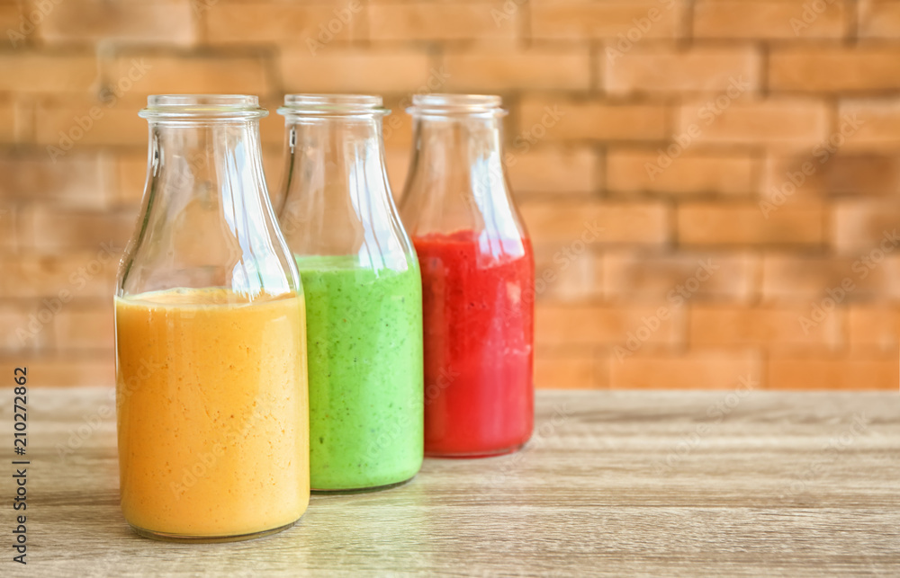 Bottles with fresh tasty smoothies on wooden table