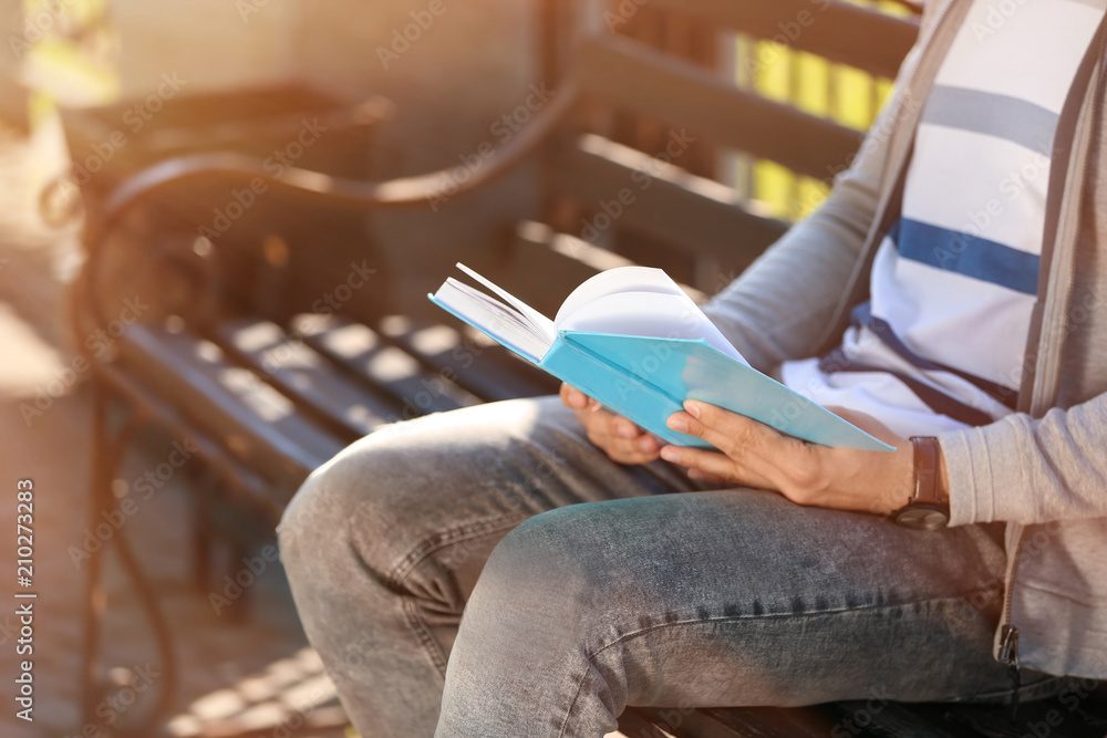 Man reading book in park, closeup