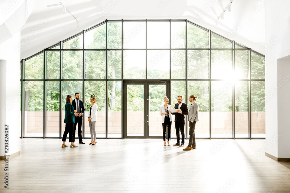 Business people at the spacious modern hall with big window overlooking on the park. Wide view with 