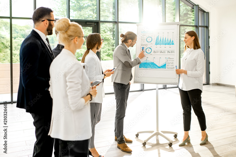 A group of business people standing together during the conference with flip chart at the modern off