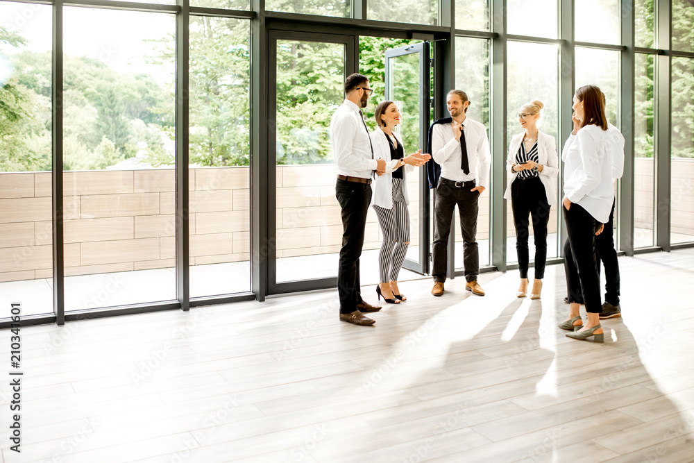 View on the modern office hall with a group of business people talking together near the window over