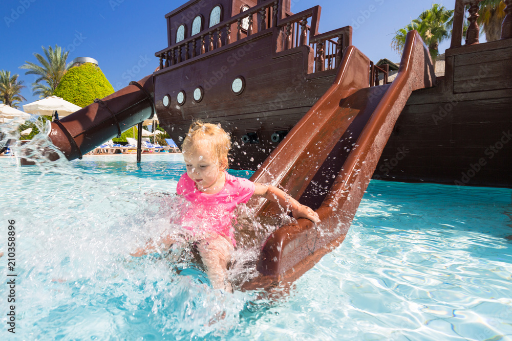 Little girl having fun at the water slide on summer holidays