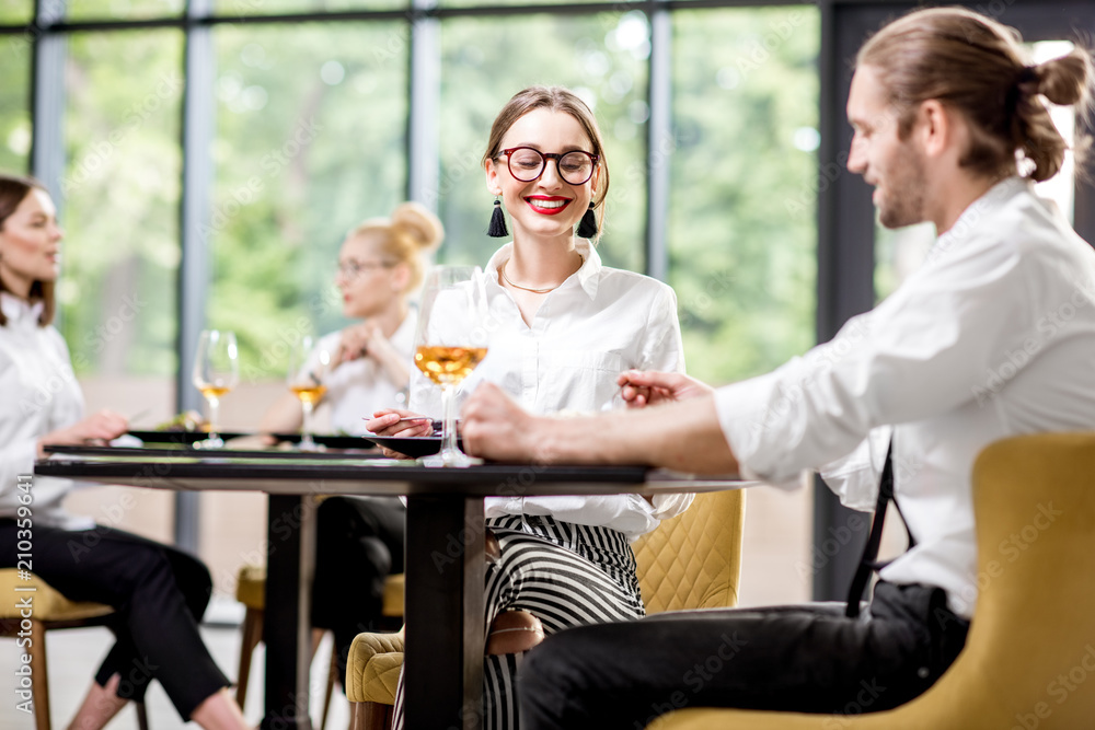 Beautiful couple clinking with wine glasses during a business lunch with delicious meals at the mode