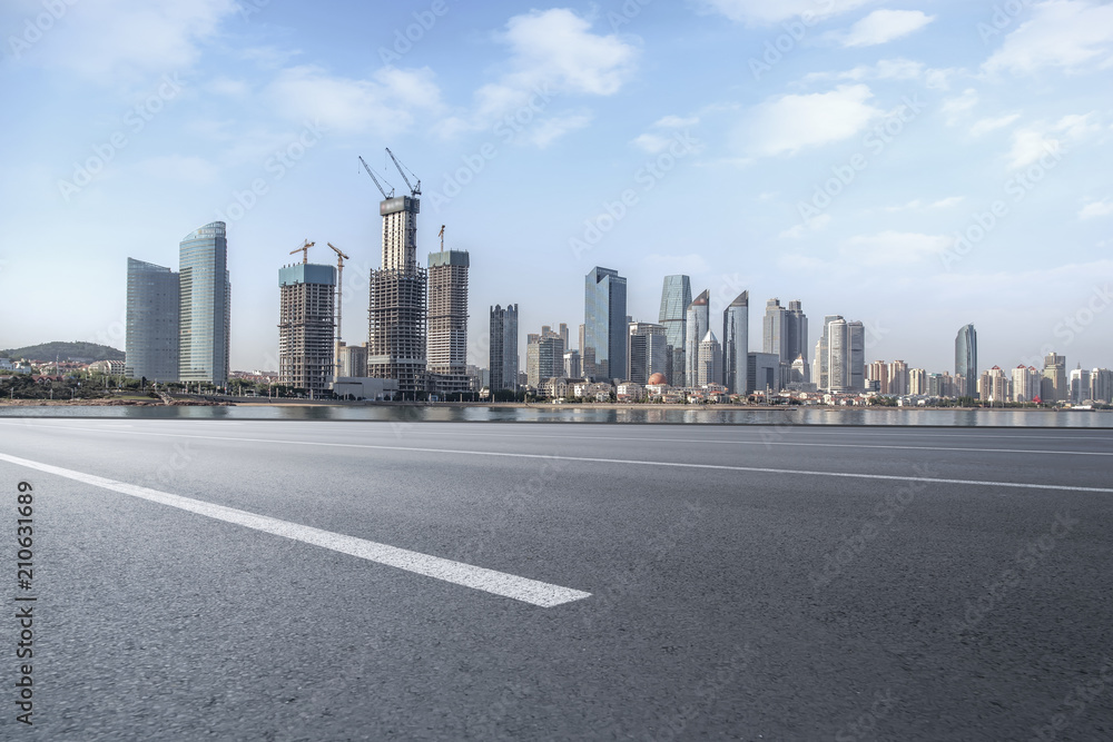 The empty asphalt road is built along modern commercial buildings in Chinas cities.