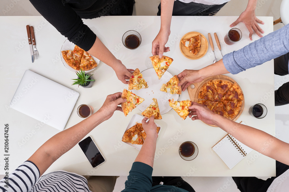 The office staff eat pizza and drink coffee in the business office. They have a break in their work.