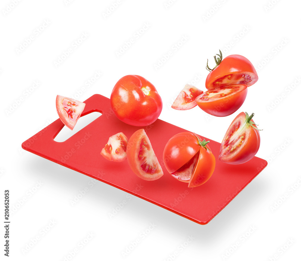 Slices of tomatoes fall on the kitchen board