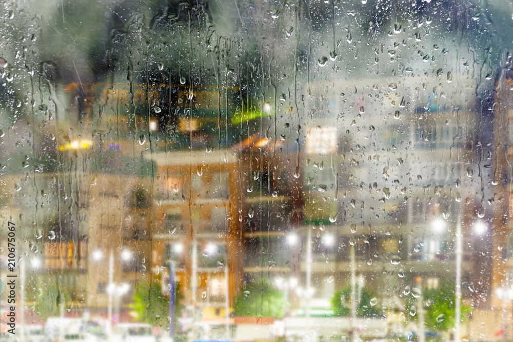 Fondo abstracto de ciudad a través de la ventana.Noche lluviosa y calles de la ciudad. Gotas de lluv