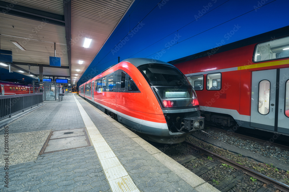 High speed train on the railway station at night. Modern intercity train on the railway platform wit