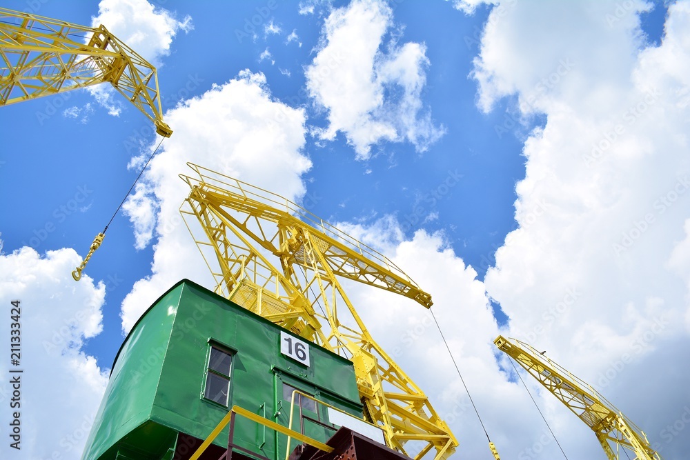 Detail of an old port crane against a cloudy sky.