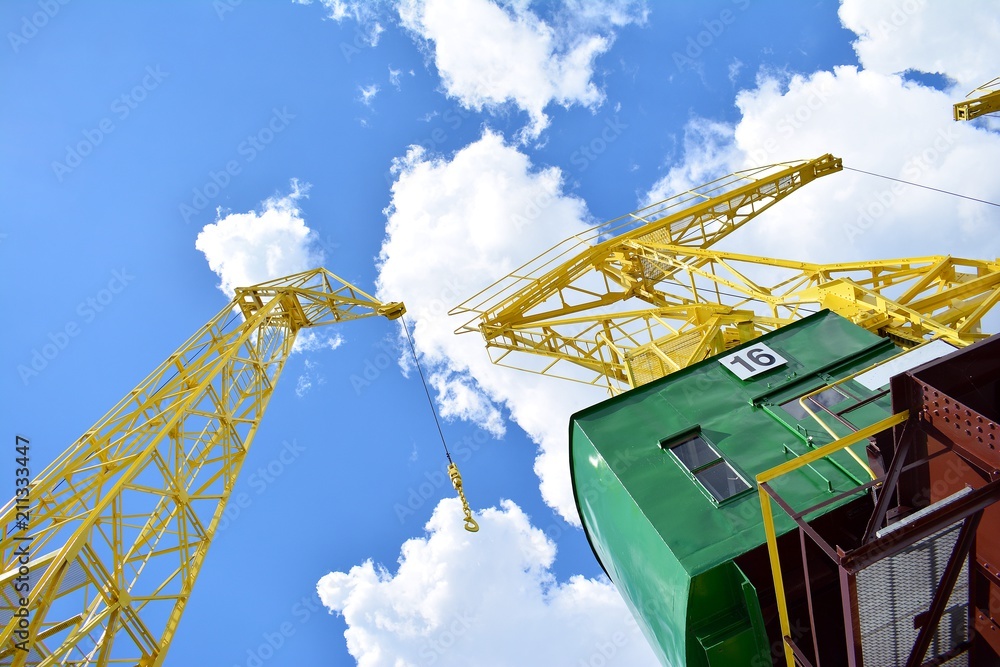 Detail of an old port crane against a cloudy sky.