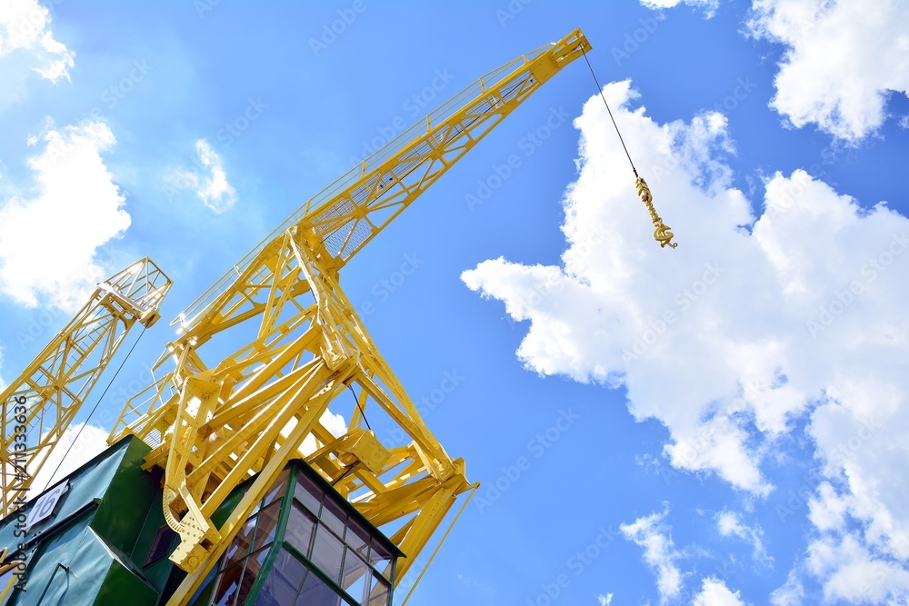 Detail of an old port crane against a cloudy sky.