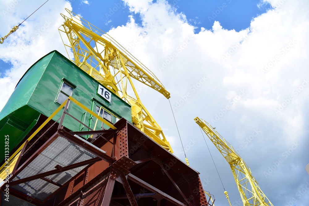 Detail of an old port crane against a cloudy sky.